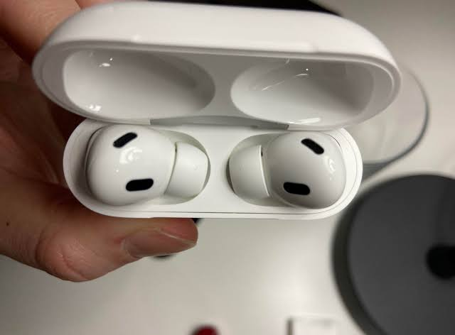 AirPods inside an open charging case near an unlocked iPhone while Find My setup completes.